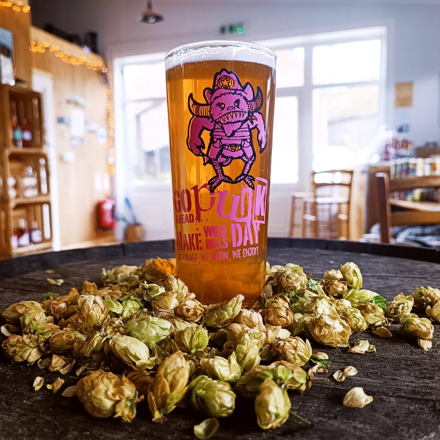 Glass of Wildcraft beer sat in a pile of aromatic hops