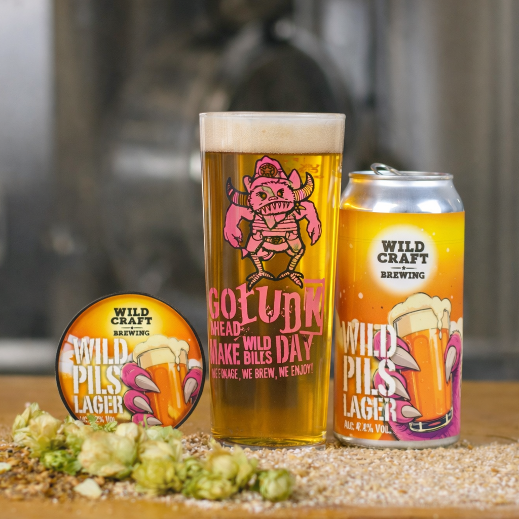 Wildcraft Brewing beer can, glass, and label on a wooden surface with a blurred background.