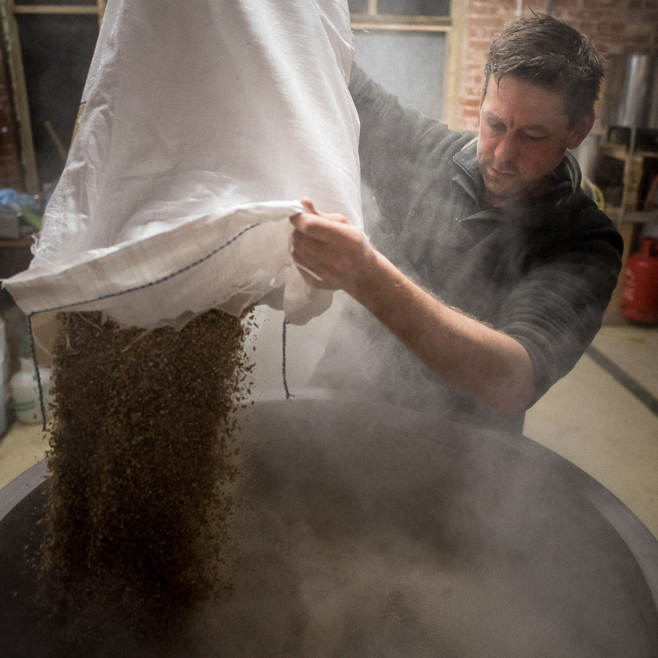 Mike in the old brewery pouring malt into the mash tun